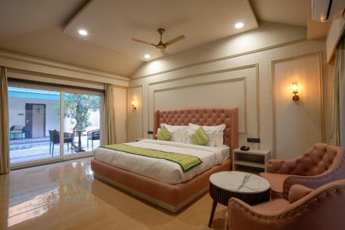 a bedroom with a bed and a chair and a window at Bageecha Resort in Pushkar