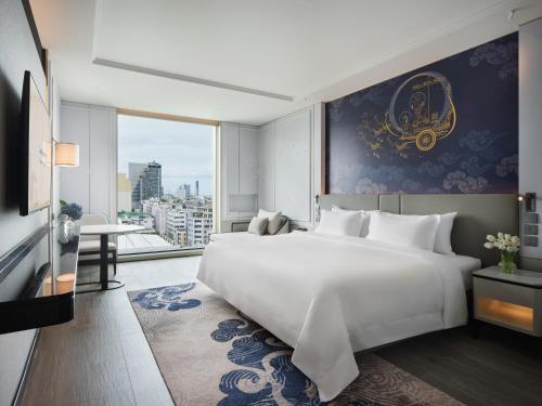 - une chambre avec un grand lit blanc et une grande fenêtre dans l'établissement Grande Centre Point Surawong Bangkok, à Bangkok