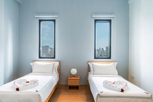 two beds in a room with two windows at Emerald Hotel Residence in Phnom Penh