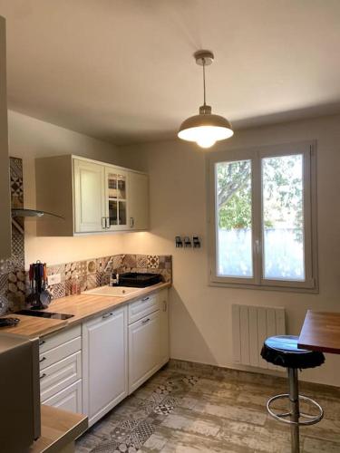 une cuisine avec des armoires blanches, une table et une fenêtre dans l'établissement Charmante Maison au pied du Luberon, à Cheval-Blanc