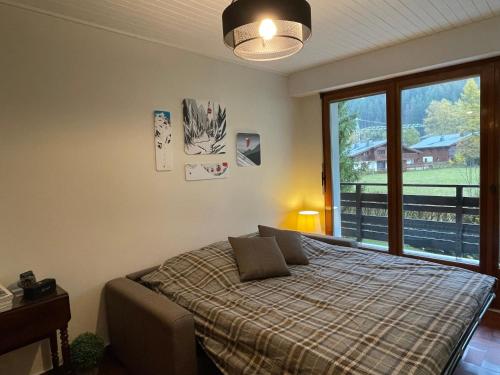 une chambre avec un lit et une grande fenêtre dans l'établissement Résidence Bois du Bouchet, appartement vue montagne, calme, parking gratuit, proche centre, à Chamonix-Mont-Blanc