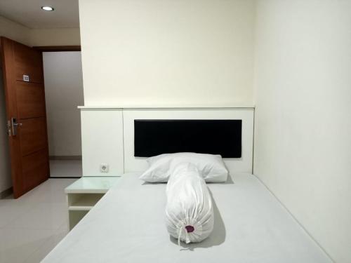 een slaapkamer met een wit bed en een hoofdeinde bij OYO 93303 Lourdes Blessing Hill in Tomohon
