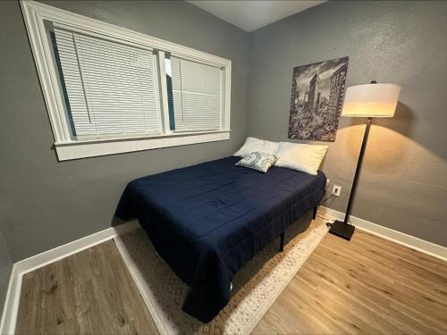 1 dormitorio con 1 cama con manta azul y ventana en Your Oakland Nest! 3bd Oasis., en Oakland