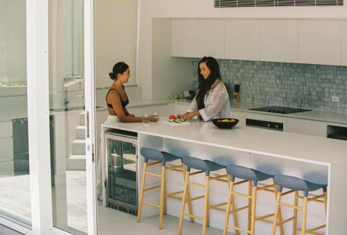 two women sitting at a counter in a kitchen at 71 Hastings Street - Beachfront in Noosa Heads