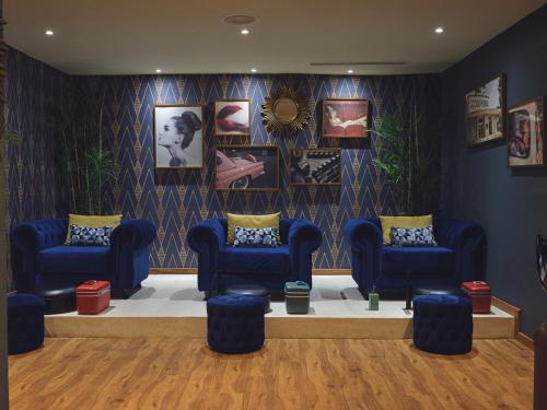 a waiting room with blue chairs and pictures on the wall at MAMAKA by Ovolo in Kuta