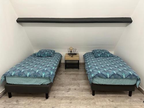 two beds in a room with a side table at Escapade entre Terre et Mer in Guilmécourt