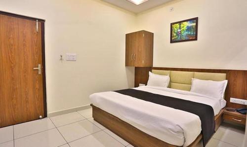 a bedroom with a large bed and a wooden door at FabHotel Prime Shree Dev Prime in Udaipur