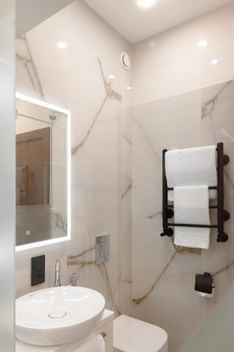 a white bathroom with a sink and a mirror at Almaty Hotel in Almaty