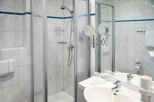 a white bathroom with a shower and a sink at Michel Hotel Hodenhagen in Hodenhagen