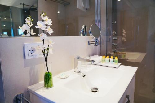 un baño con lavabo blanco con un jarrón de flores en Marton Valldemossa Turismo de Interior, en Valldemossa