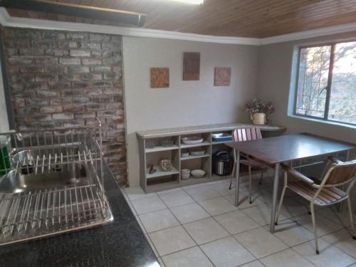uma cozinha com uma mesa e cadeiras e uma parede de tijolos em Hartbees Boskamp em Dinokeng Game Reserve