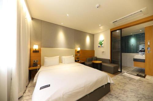 a bedroom with a large white bed and a bathroom at Brooks Business in Changwon