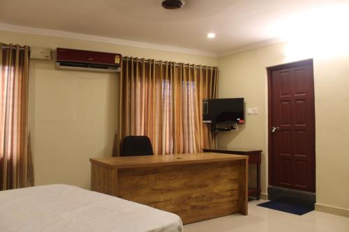 1 dormitorio con escritorio, TV y cama en LILLY RESIDENCY by Chungath, en Perumpāvūr