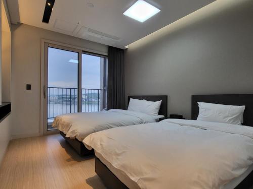 two beds in a room with a large window at World State Hotel Sokcho in Sokcho