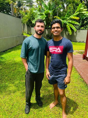 two men standing next to each other in the grass at Urban Galle Villa in Galle