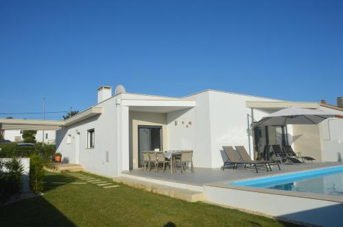 a white house with a swimming pool and a patio at Casa Alegria Nadadouro in Nadadouro
