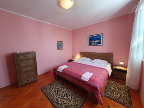 ein Schlafzimmer mit einem Bett mit rosa Wänden und einer Kommode in der Unterkunft SANDRA A4, 80 m FROM THE BEACH in Novigrad Istria