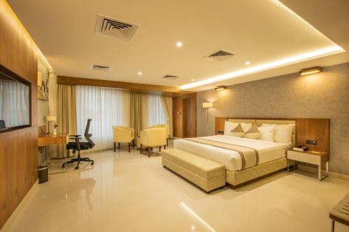 Habitación de hotel con cama, escritorio y silla en Royal Plaza Suites, en Mangalore