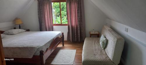 1 dormitorio con cama, sofá y ventana en Loversnest Self Catering en Anse aux Pins