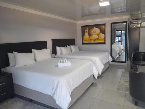 Habitación de hotel con 2 camas con sábanas blancas en TONY'S GUEST HOUSE 2 en Mahikeng