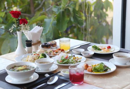 a table with plates of food and drinks on it at Hoang Long Hotel Phan Thiết in Phan Thiet