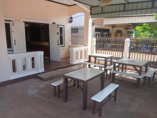 a group of tables and benches in front of a building at Bolaven trail guesthouse in Pakse