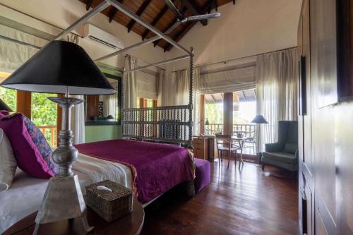 a bedroom with a bed and a table with a lamp at Eraeliya Villas & Gardens in Weligama