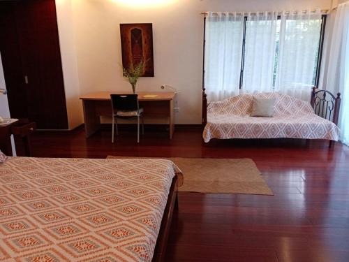 a bedroom with two beds and a desk and a table at Linden Beach Talikud in Santa Cruz