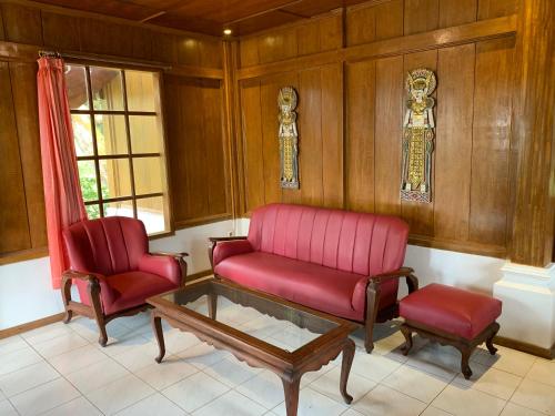 a living room with two red chairs and a coffee table at Villa Kayu Puncak by Henny Ariastoeti in Campaka
