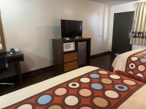 a hotel room with two beds and a flat screen tv at Super 8 by Wyndham Giddings in Giddings
