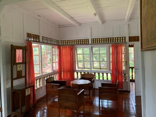 a room with red curtains and a table and chairs at Villa Kayu Puncak by Henny Ariastoeti in Campaka