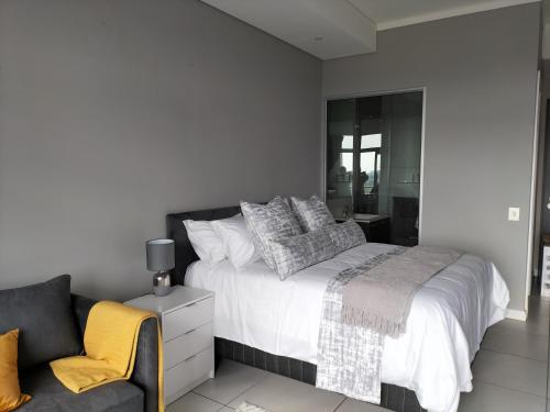 a white bedroom with a bed and a couch at Lizzy's Exclusive Studio in Pretoria