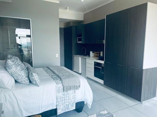 a bedroom with a large bed and a kitchen at Lizzy's Exclusive Studio in Pretoria