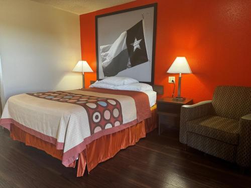 a hotel room with a bed and a chair at Super 8 by Wyndham Giddings in Giddings