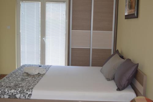 a bedroom with a white bed and two windows at Apartments Lalević in Donji Morinj
