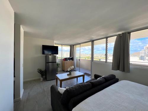 a bedroom with a bed and a couch and a tv at Penthouse in Waikiki with ocean & mountain views in Honolulu