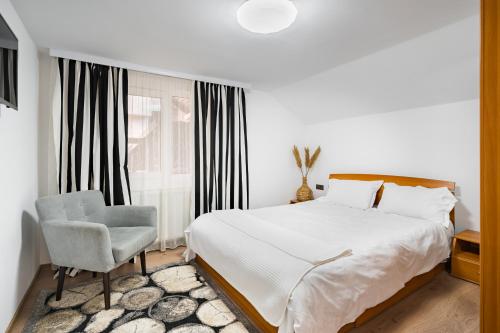 a bedroom with a bed and a chair and a window at Acasă la Doftana in Teşila