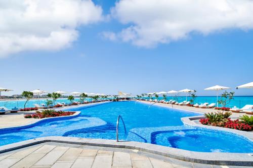 a swimming pool at a resort with the ocean in the background at Address Beach Resort Marassi in El Alamein