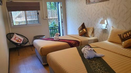 a hotel room with two beds and an elephant toy on a table at บ้านสวนในฝัน-ตลาดน้ำท่าคา in Samut Songkhram