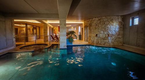 a swimming pool in a hotel with a stone wall at Mulberries in Żabbar