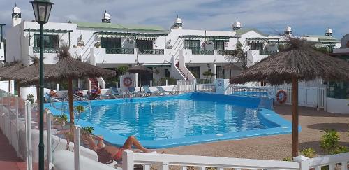 una piscina con sillas junto a un hotel en SunnyDaze, en Tías