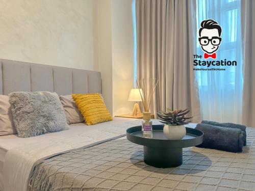 Staycation Homestay 31 Skyvilla Condominium near MJC في كوتشينغ: غرفة نوم مع سرير وطاولة مع علامة