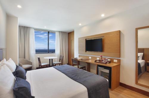 a hotel room with a bed and a desk and a television at Windsor Excelsior Copacabana in Rio de Janeiro