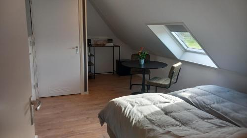 a bedroom with a bed and a table and a window at B&B t'bûtefjild in De Valom