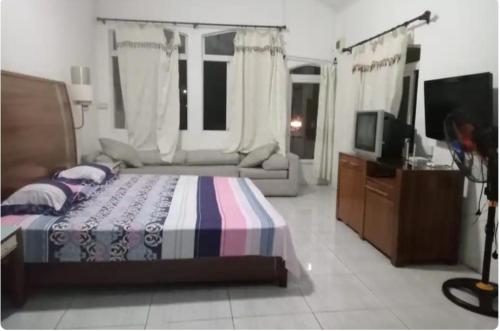 een slaapkamer met een bed en een tv en een bank bij Cheerful 1 bed vacation home with tours & facilities in La Gaulette