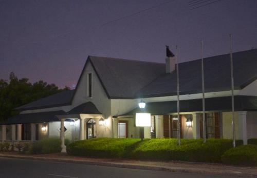 a white building with a black roof at night at Old House Lodge in Beaufort West