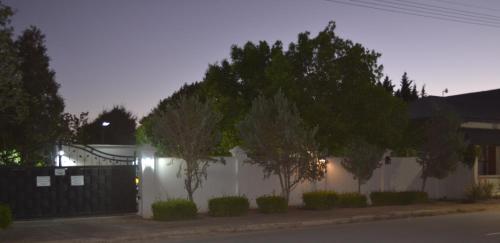 a white fence with trees in front of a house at Old House Lodge in Beaufort West