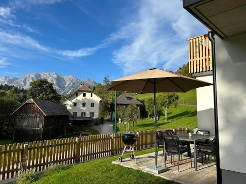a patio with an umbrella and a table and chairs at Mei-so-nett Appartement Hutegger in Schladming