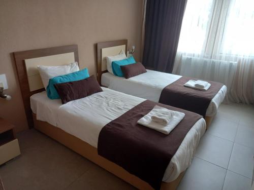 2 Betten in einem Hotelzimmer neben einem Fenster in der Unterkunft Kumru Suites in Sarıcaeli