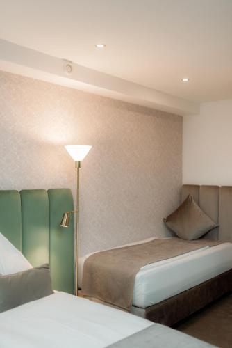 a hotel room with two beds and a lamp at NED Hotel in Graz